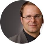 Ein Mann mit Brille, er lächelt