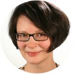 Eine Frau mit braunen Haaren und Brille, sie lächelt