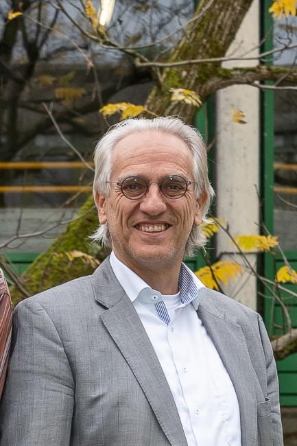 Porträt vor einem Strauch in der Natur von Prof. Dr. Christoph Weller