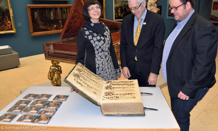Pia Praetorius blickt gemeinsam mit Ulrich Großmann, Direktor des Germanischen Nationalmuseums Nürnberg, und Produzent Andreas Meixner auf ein Egidien-Choralbuch, aus dem die Stücke der neuen CD stammen.