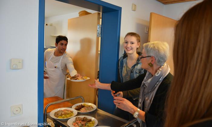 Dreikönigsessen in der Markusgemeinde Regensburg: Helfer bringen das Hauptgericht aus der Küche in den Speisesaal.