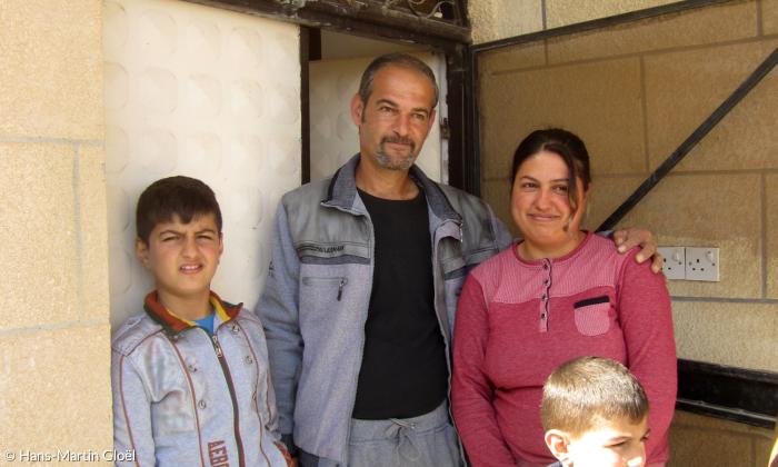 Vor wenigen Tagen sind Afra und ihr Mann Aziz in ihr Haus in Telskuf zurückgekehrt. Mit den Söhnen Andi (10) und Even (5) stellen sie sich unter dem Kreuz vor der Haustüre für ein Foto auf.