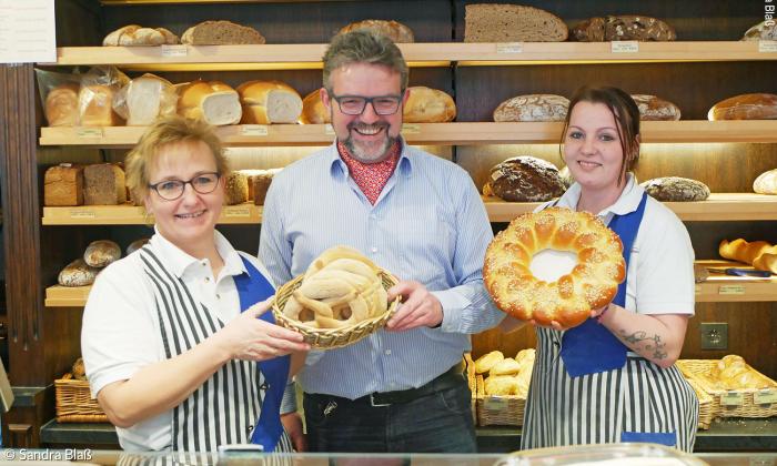 Bäckermeister Thomas Zimmer mit zwei Mitarbeiterinnen und Anisbrezeln und Eierring