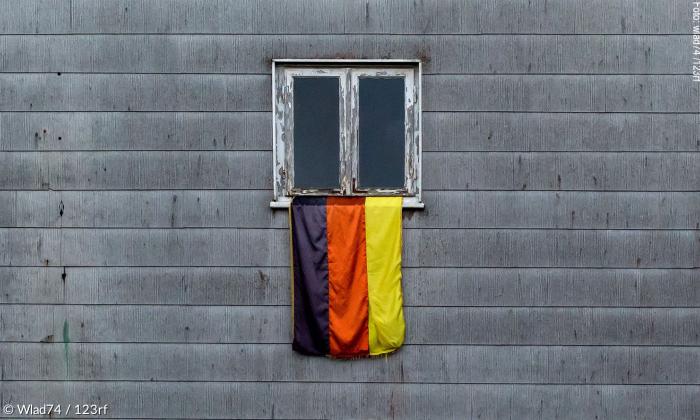 Deutschlandfahne vor grauer Hauswand.