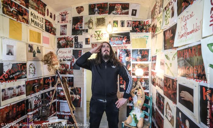 Jonathan Meese inmitten seiner Arbeit »ERZTARZAN’S ZELLE, DIE 95 KUNSTTHESEN DESTEUFELS(BABIES) ALASKA KIDADDY MACHT DAS RENNEN „K.U.N.S.T.“ (M.E.E.S.E. IST JOHNNY SINCLAIR)«, 2017, Mischtechnik (»Luther und die Avantgarde«, Wittenberg).