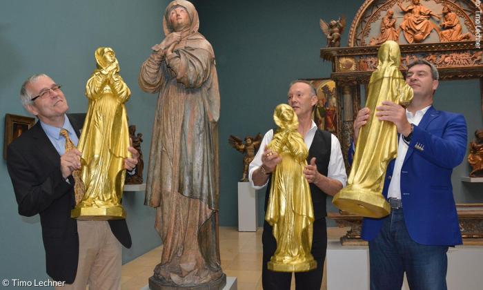 Museumsleiter Ulrich Großmann, Konzeptionskünstler Ottmar Hörl sowie Staatsminister und Schirmherr Markus Söder mit drei Prototypen der Gold-Madonnen und dem Original.
