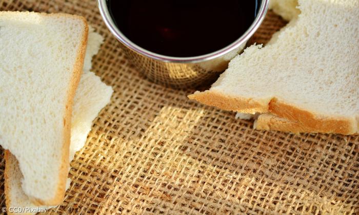 Bächer Wein mit Brot auf einem Tuch mit Kreuzzeichen 