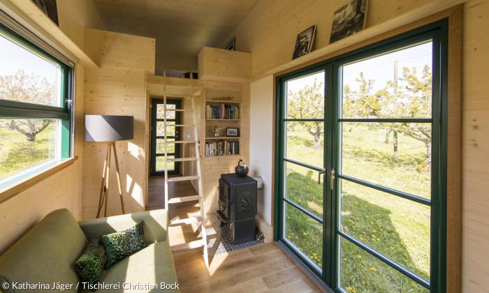 Über eine Leiter geht es in die Galerie zum Schlafbereich. Die enorme Deckenhöhe und die großen Fenster lassen das Minihaus gleich viel größer wirken.