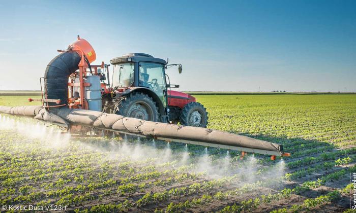 Traktor versprüht Pestizide auf Feld.