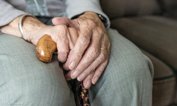 Hände einer älteren Person mit Gehstock 