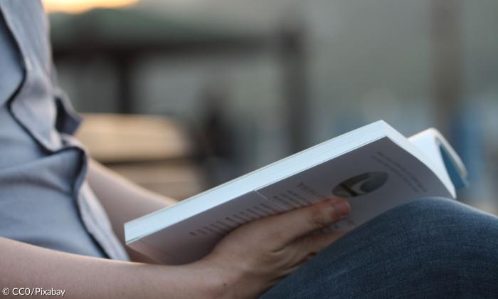 Sitzender Mann mit aufgeschlagenem Buch 