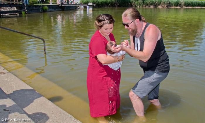 Pfarrer Andy Gatz tauft ein Kind im Kemptener Bachtelweiher