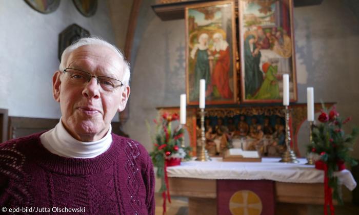 Kirchenarchivar Ewald Glückert vor dem Hochaltar der Egidienkirche in Beerbach aus der Werkstatt von Michael Wolgemut.