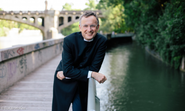 Ein Mann lehnt auf einer Brücke, unter ihm Wasser