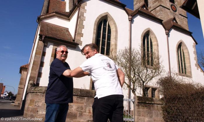 Wolfgang Victor und Pfarrer Christian Schmidt beim coronakonformen Gruß vor der Egidienkirche Eltersdorf