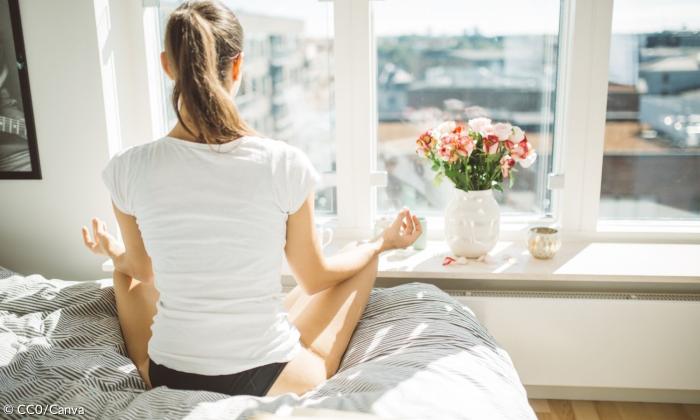Frau meditiert auf dem Bett