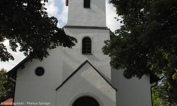 Wo einst ein rotes Leuchtfeuer brannte: Pfarrhelfer Robert Jörend deutet auf das Turmkreuz der Campuskirche Neubiberg.