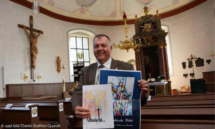 Pfarrer Claus Ebeling in der Lichtenauer Dreieinigkeitskirche mit Entwürfen für ein Buchcover. 
