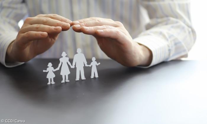 Zwei Hände, schützend über eine Familie gehalten