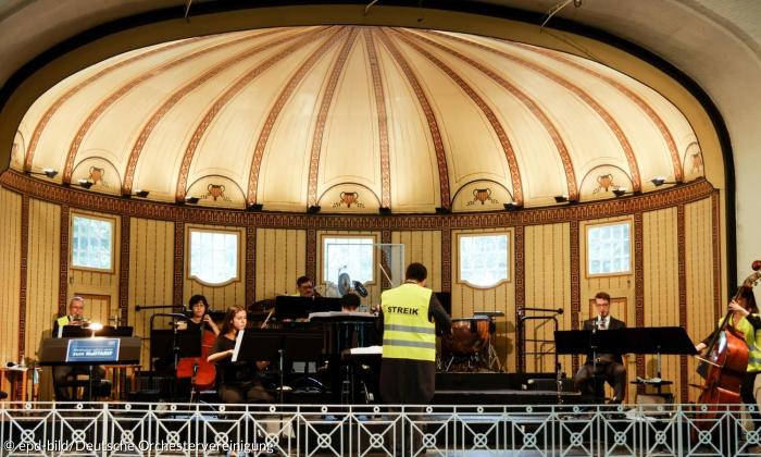 Die Musiker und Musikerinnen der Philharmonie Bad Kissingen in Warnwesten mit der Aufschrift "Streik" bei einem Auftritt