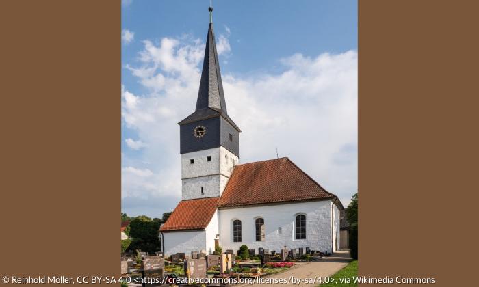 Die Kirche in Weisendorf. Davor ist ein Friedhof, der Himmel ist blau.