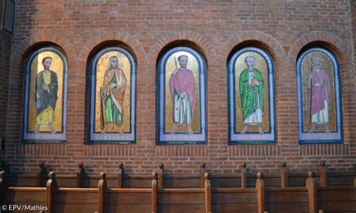 Bilder verschiedener Männer auf einem Goldgrund in der Kirchenwand.