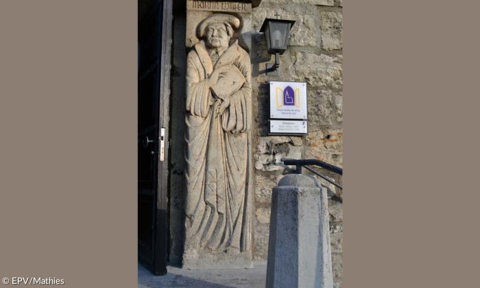 Eingang zur Kirche mit einer Säule, in der Martin Luther eingemeißelt ist, daneben.