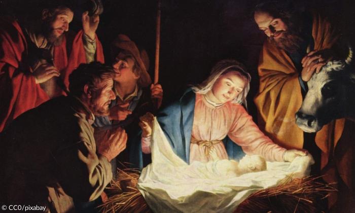 Das Jesuskind in der Krippe. Daneben sitzen Maria und Josef, Hirten und eine Kuh.