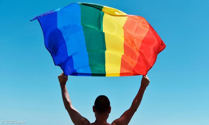 Ein Mann mit der Regenbogenfahne