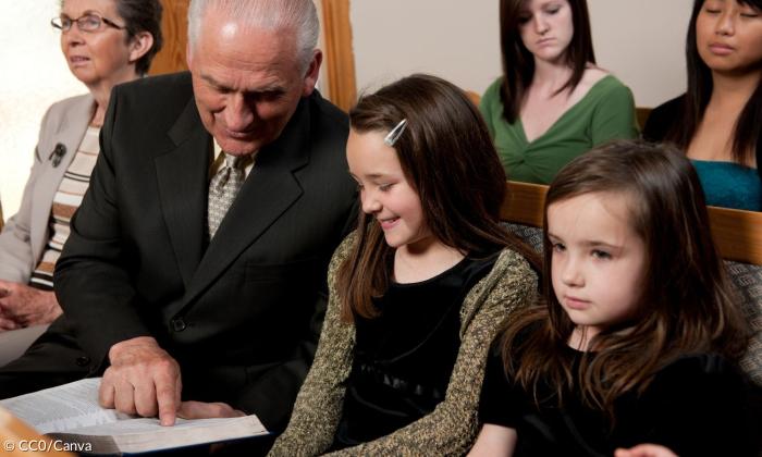 Ein alter Mann zeigt einem Mädchen im Gottesdienst eine Stelle in der Bibel