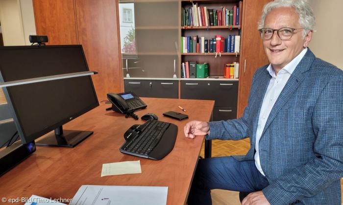 Ein Mann im blauen Anzug sitzt am Schreibtisch