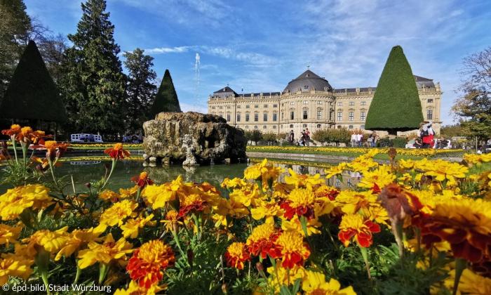Ein Schloss, im Vordergrund sieht man blühende Blumen