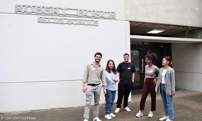 Fünf junge Menschen stehen vor der Schule