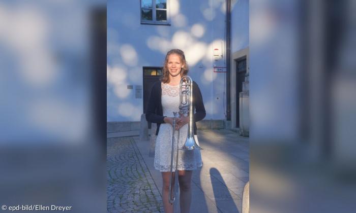 Eine junge Frau in einem Kleid mit einer Posaune
