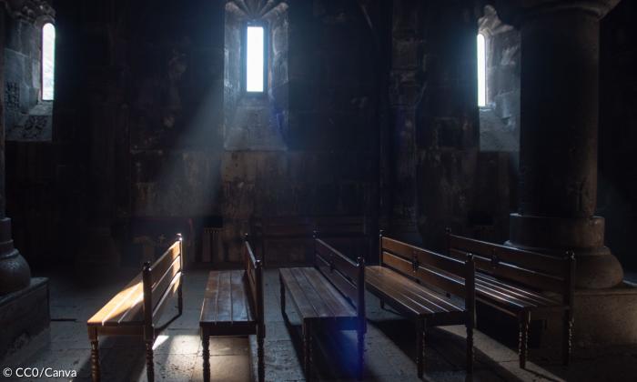 Der Innenraum einer Kirche mit dicken Mauern, durch die schmalen Fenster fällt ein Sonnenstrahl