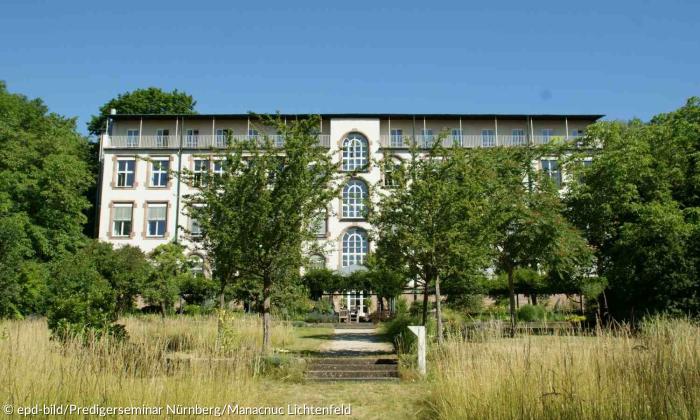 Ein Haus hinter Bäumen, darüber der blaue Himmel