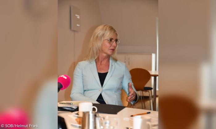 Ulrike Scharf am Tisch mit einem Mikrofon