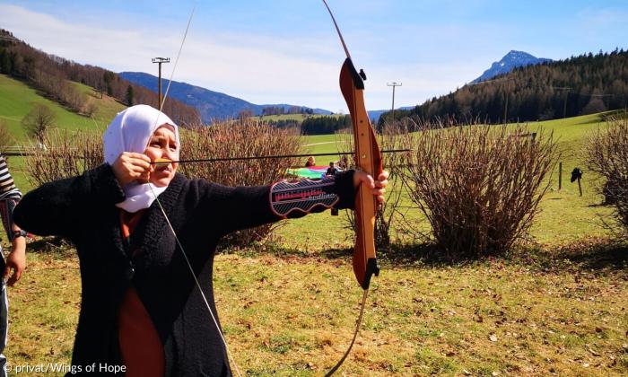 Frau mit Bogen vor Berglandschaft