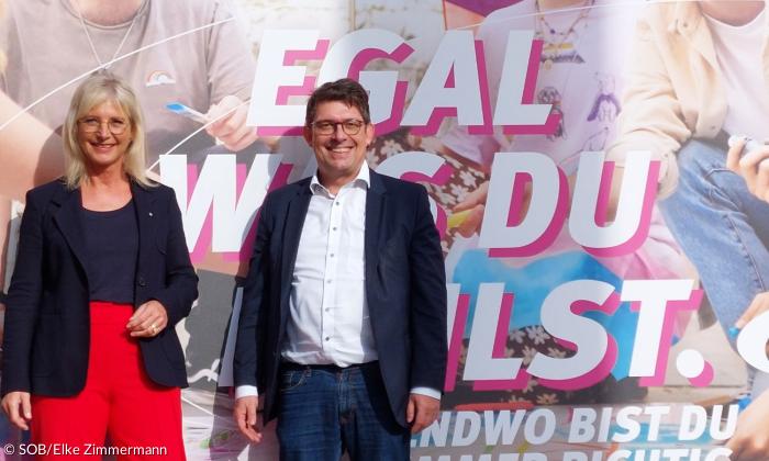 Eine Frau und ein Mann vor einem Plakat
