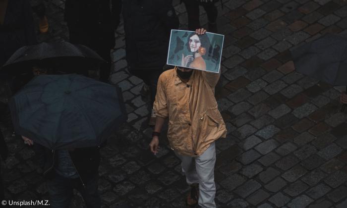 Ein Mann hält ein Bild von Jina Mahsa Amini