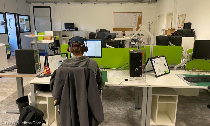 Ein Büro, in dem jemand am Schreibtischen sitzt und arbeitet