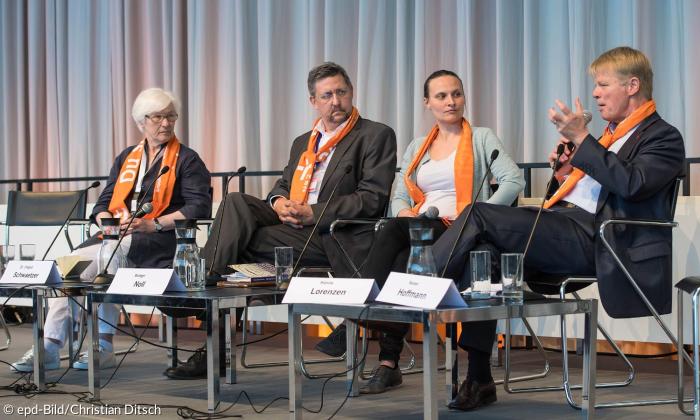 Vier Menschen sitzen auf einem Podium