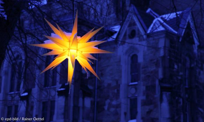 Leuchtender Herrnhuter Weihnachtsstern in der Abenddaemmerung