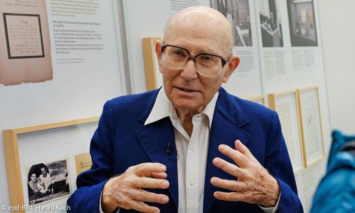 Ein Mann mit großer Brille in einem blauen Anzug.