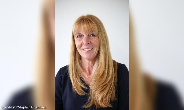 Porträtbild einer Frau mit rotblonden langen Haaren und Pony. Sie lächelt und trägt ein dunkelblaues Oberteil.