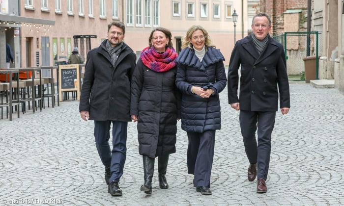 Zwei Männer und zwei Frauen in Winterkleidung in einer Fußgängerzone