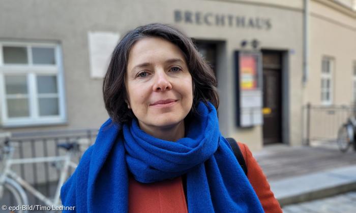 Eine Frau mit einem blauen Schal vor dem Brechthaus