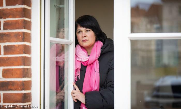 Eine Frau steht am Fester und schaut hinaus