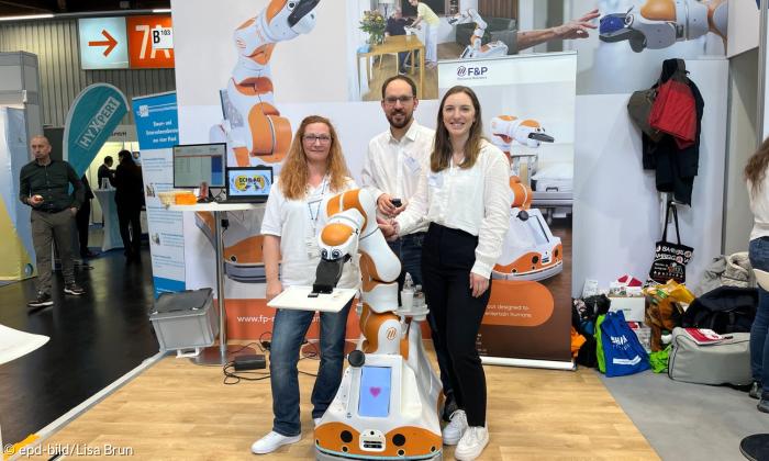 Drei Personen und ein Roboter.