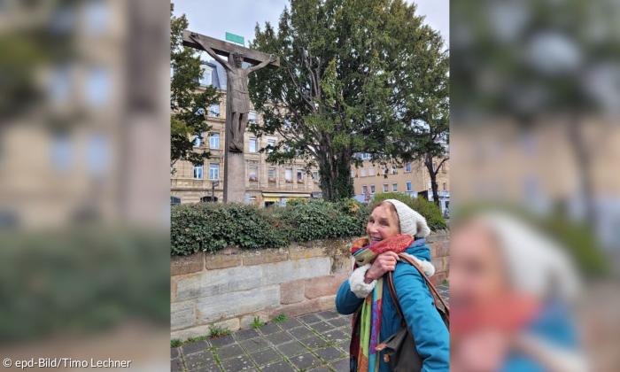 Eine Frau mit Mütze vor einem Kruzifix